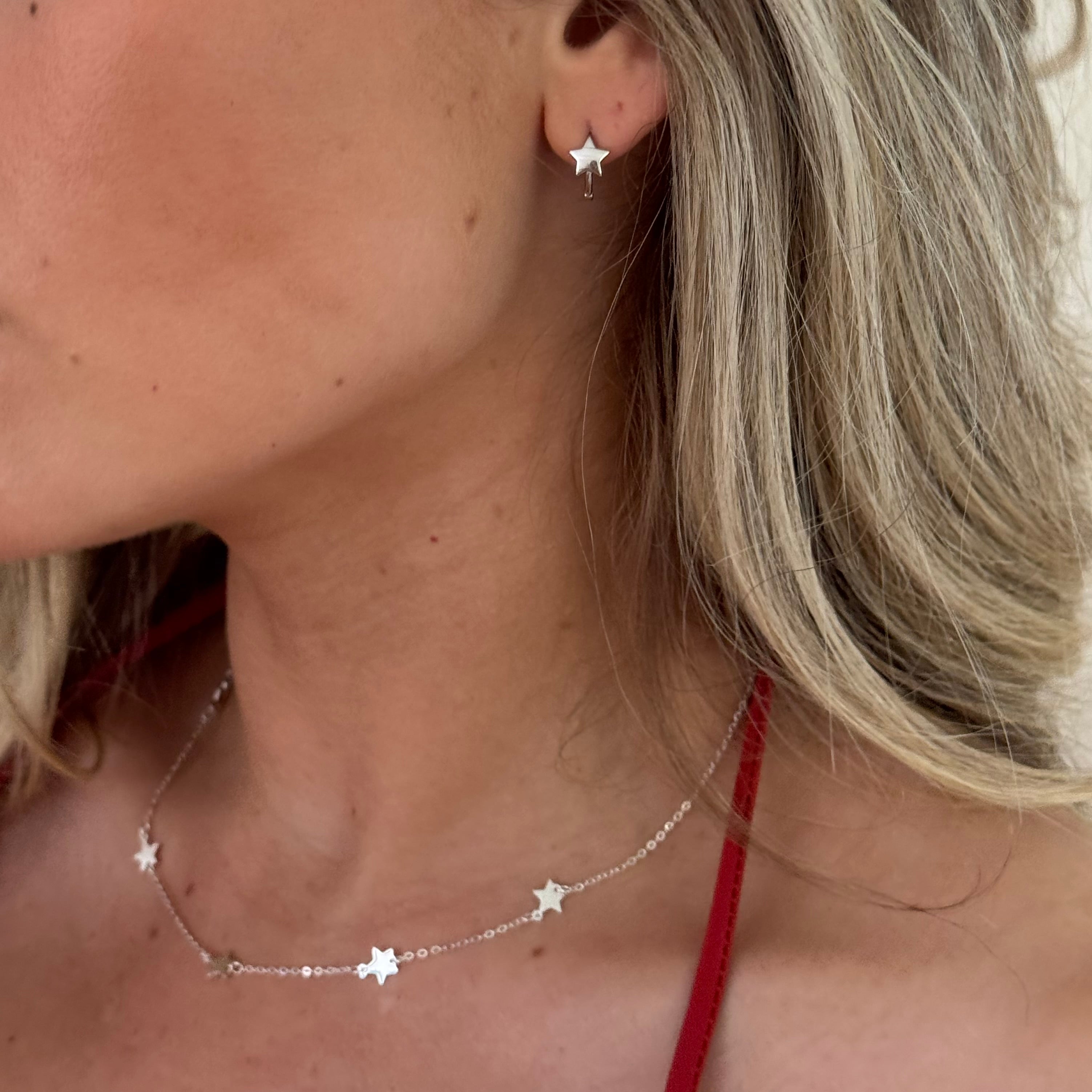 Close-up of a person wearing a star-shaped earring and necklace.