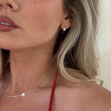 Close-up of a woman wearing star-shaped earrings and a necklace with a neutral background