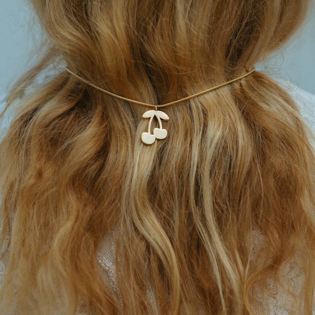 Blonde hair tied back with a decorative hair tie against a neutral background