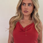 Woman wearing a red top with a necklace against a plain background