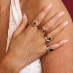 Hand wearing multiple rings with gemstones on a blurred background