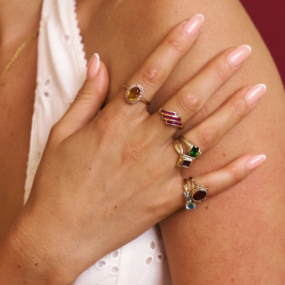 Hand wearing multiple rings with gemstones on a blurred background