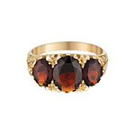 Gold ring with three dark red garnet gemstones on a white background