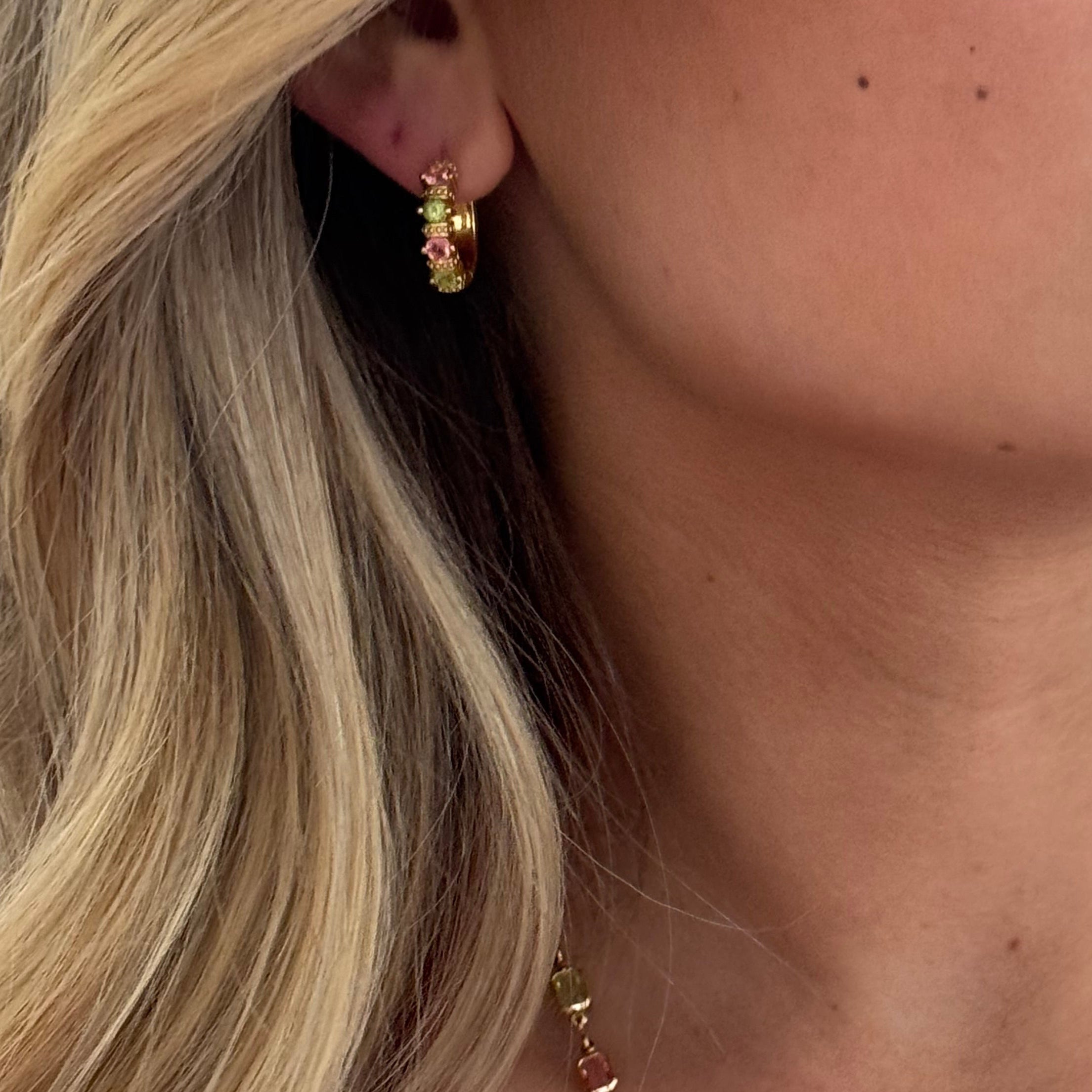 Close-up of a woman wearing a colorful beaded necklace and gold earrings.