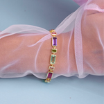 Multicolored gemstone bracelet on a wrist with sheer fabric background