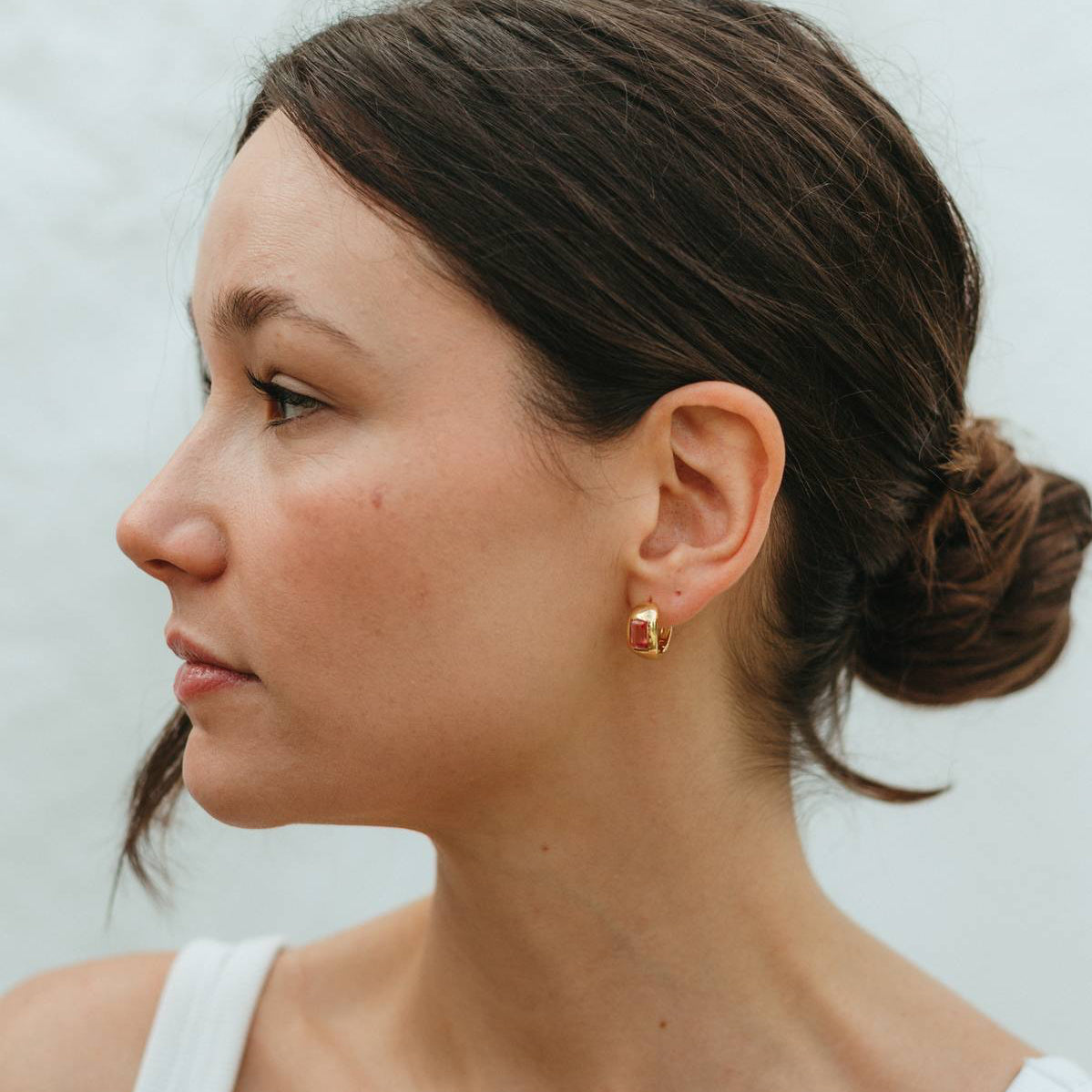 Woman wearing gold earrings with a neutral background