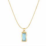 Gold necklace with a blue gemstone pendant on a white background