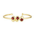 Gold bracelet with three red gemstones on a white background