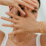 Woman wearing a gold chain necklace with a plain background