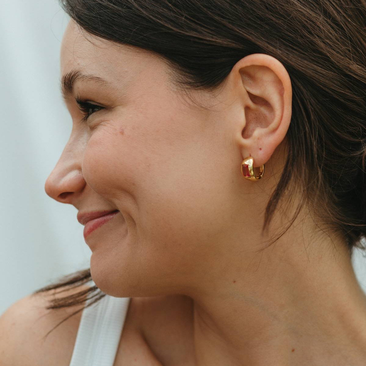 Close-up of a woman wearing a gold earring with a blurred background