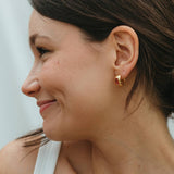 Close-up of a woman wearing a gold earring with a blurred background