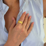 Close-up of a hand wearing a gold ring with a white garment in the background