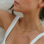 Close-up of a person wearing a gold necklace with a white top.