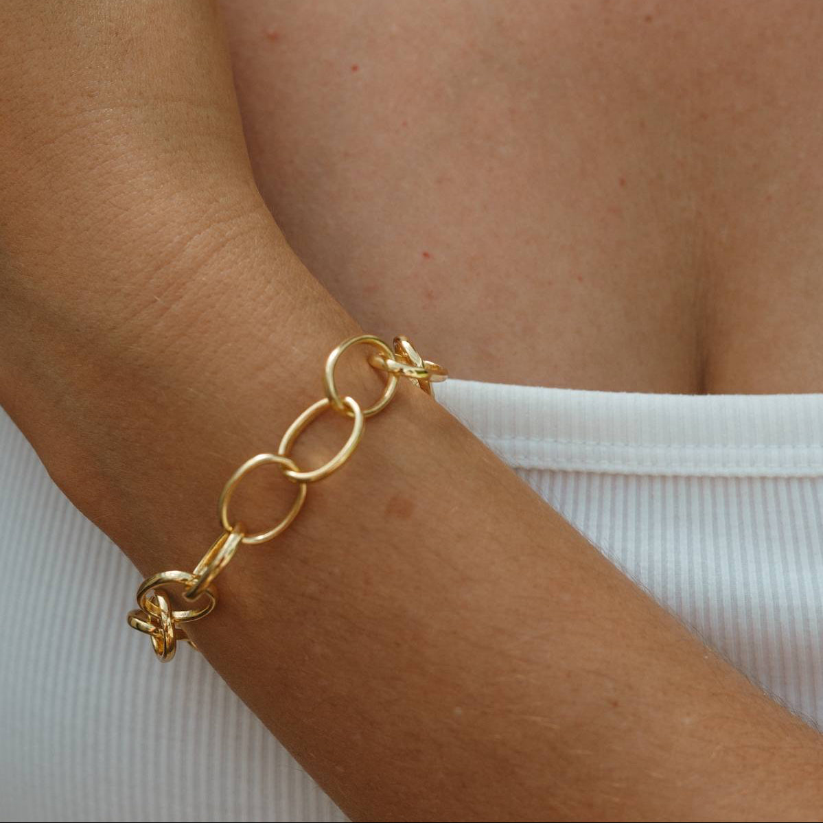 Gold chain bracelet on a wrist with a blurred background