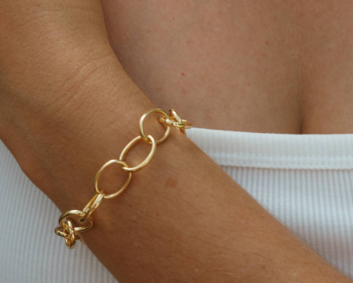 Gold chain bracelet on a wrist with a blurred background
