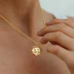 Gold necklace with a round pendant worn by a person