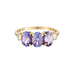 Gold ring with three oval purple amethyst gemstones on a white background