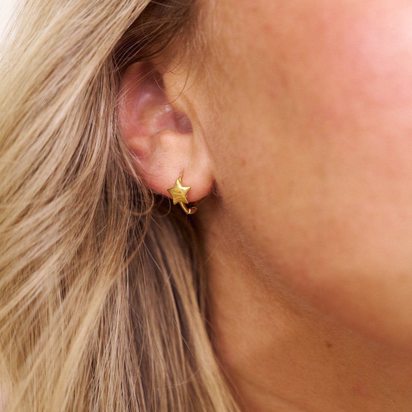 Close-up of a person wearing a gold star-shaped earring.