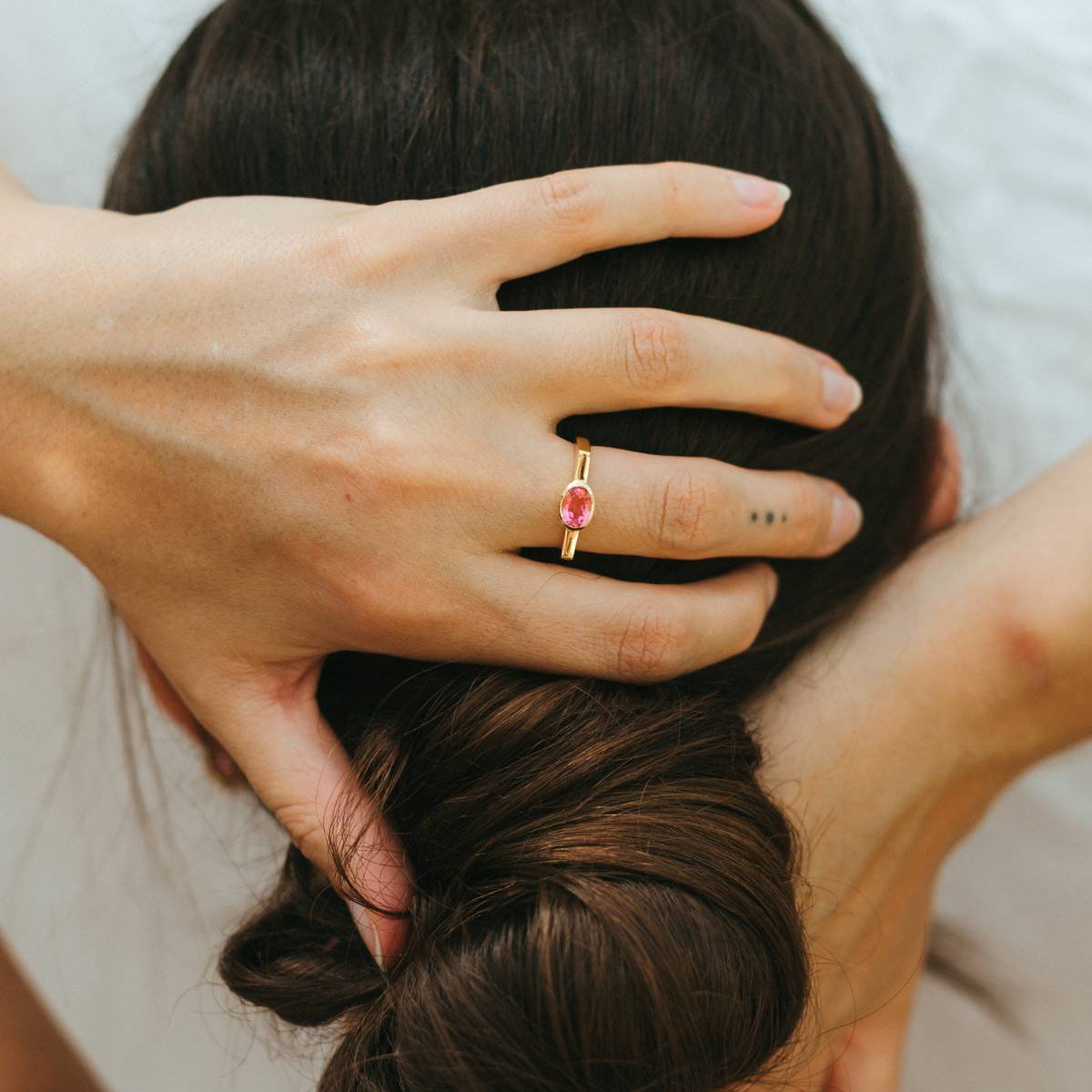 Person styling another person's hair with a close-up of a hand wearing a ring.