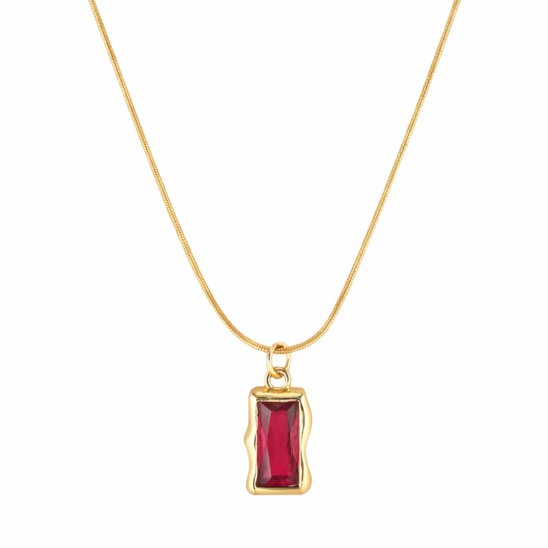 Gold necklace with a red gemstone pendant on a white background