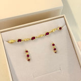 Gold bracelet and earrings with red stones in a jewelry box