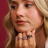 Close-up of a woman's face with three rings on her finger against a red background
