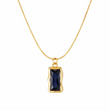 Gold necklace with a blue gemstone pendant on a white background