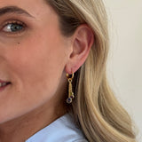 Close-up of a person wearing a gold earring with a white background