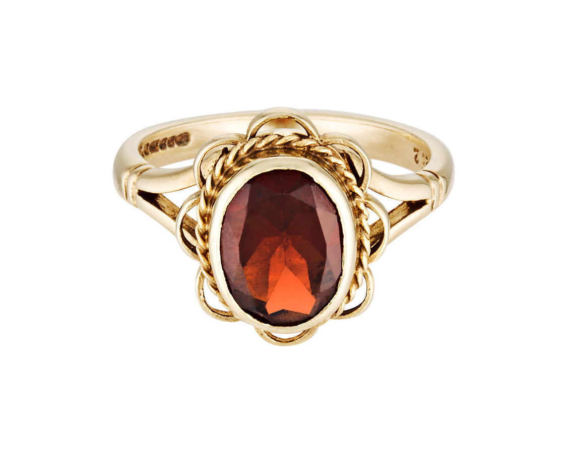 Gold ring with a red gemstone on a white background