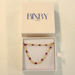 Gold and red beaded necklace in a Bixby box on a beige background