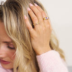 Woman with blonde hair wearing multiple rings on a blurred background