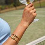 Hand holding a clear plastic cup with a small object on a tennis court