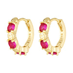 Gold hoop earrings with red gemstones on a white background