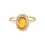 Gold ring with a yellow gemstone on a white background