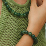 Person wearing a green beaded necklace and bracelet, close-up on green tank top.