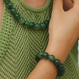 Person wearing a green beaded necklace and bracelet, close-up on green tank top.