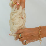 Close-up of hands with gold jewelry holding a piece of dough against a light background