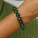 Green beaded bracelet on a wrist with a blurred green background