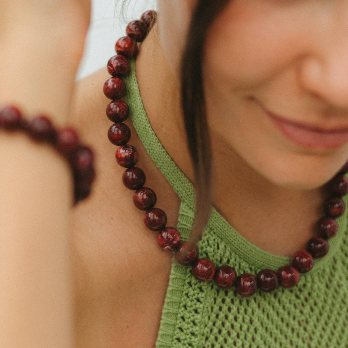 Close-up of a woman wearing a green top and red beaded necklace.