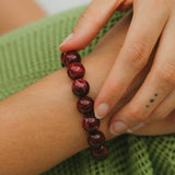 Close-up of a hand wearing a red beaded bracelet on a green fabric background