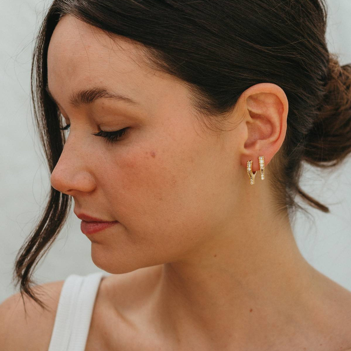 Woman wearing gold hoop earrings against a neutral background