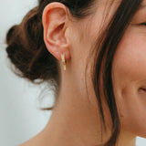 Close-up of a person wearing a gold earring with a blurred background