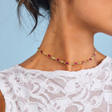 Close-up of a woman wearing gold earrings and a necklace with a blue background