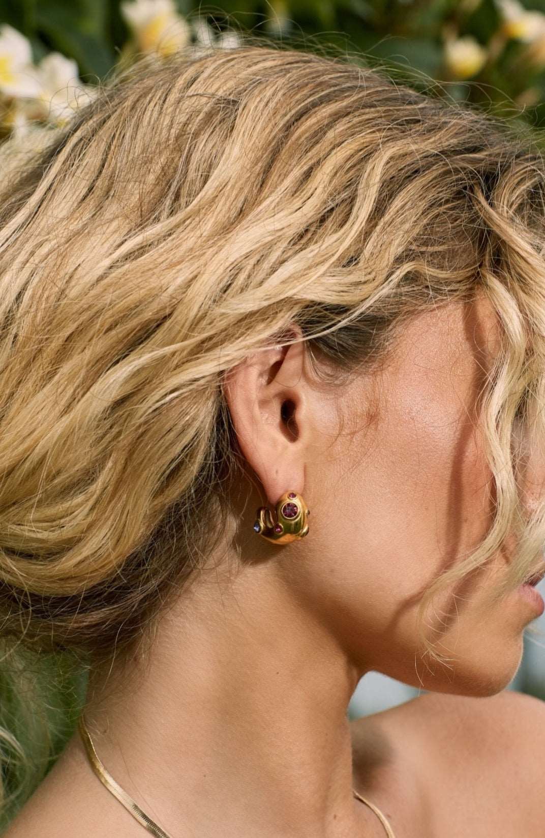 Pink and purple coloured gemstone earrings on blonde girl